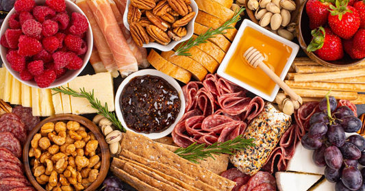 A delicious-looking charcuterie board with honey and an assortment of meats, bread, cheese, fruit, and nuts.