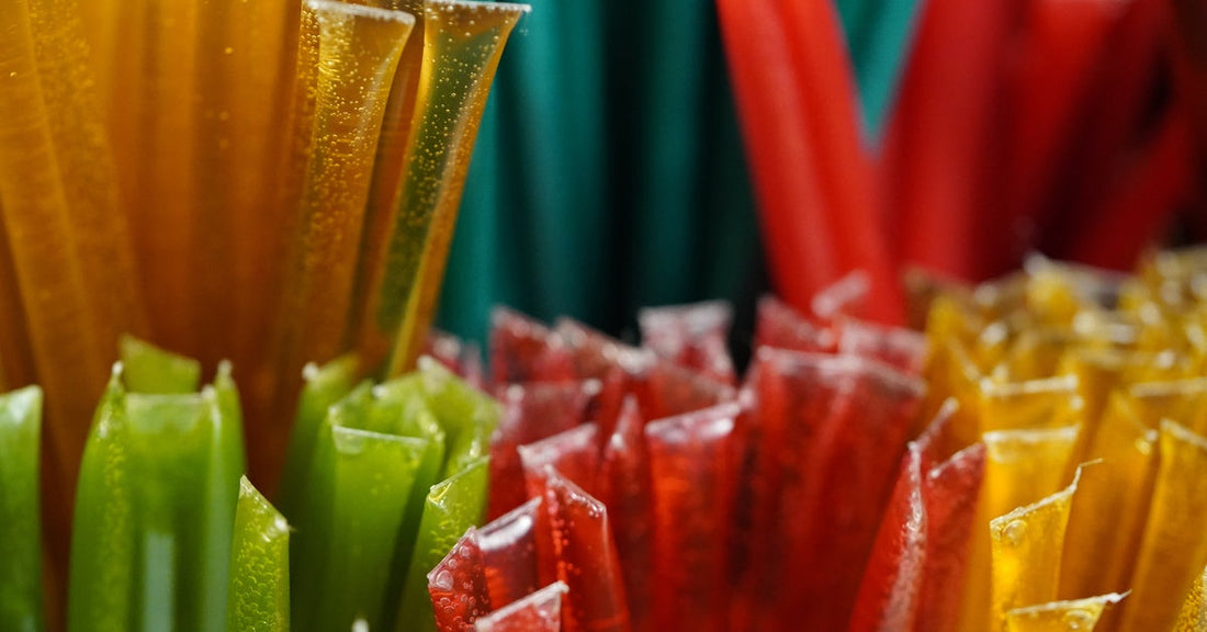 Bunches of red, green, blue, and yellow honey sticks stand grouped together by their color or flavor.