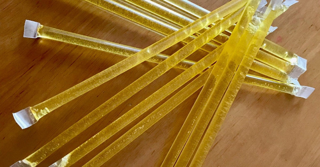 everal yellow light sticks lying on wood table, showing translucent tubes filled with glowing liquid inside.